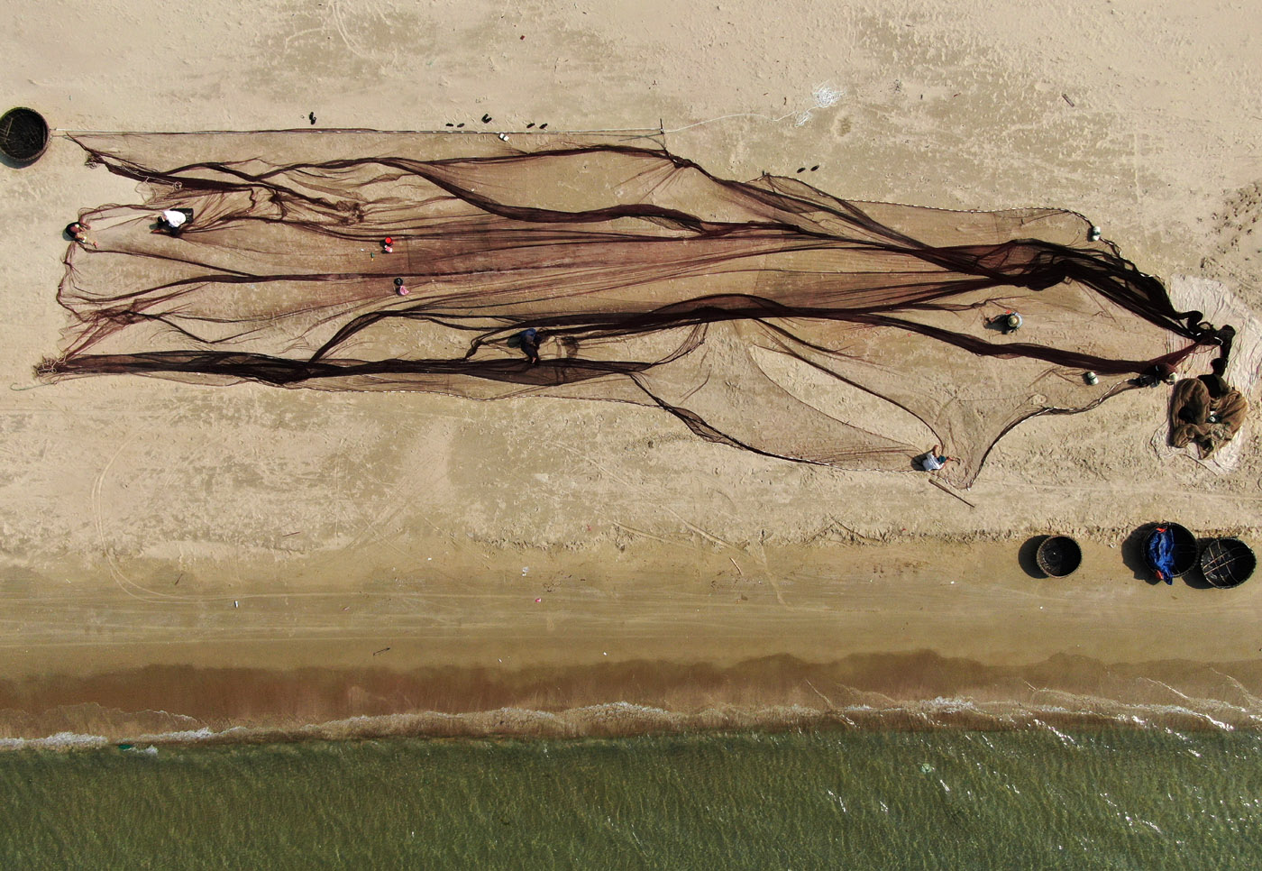 There are 750 households with more than 2.000 people working in the fishery field in this area (including directly carrying out deep-sea fishing and other occupations making money from marine resources). In this photo, the fishers are stitching the net used for fishing by blinds.
