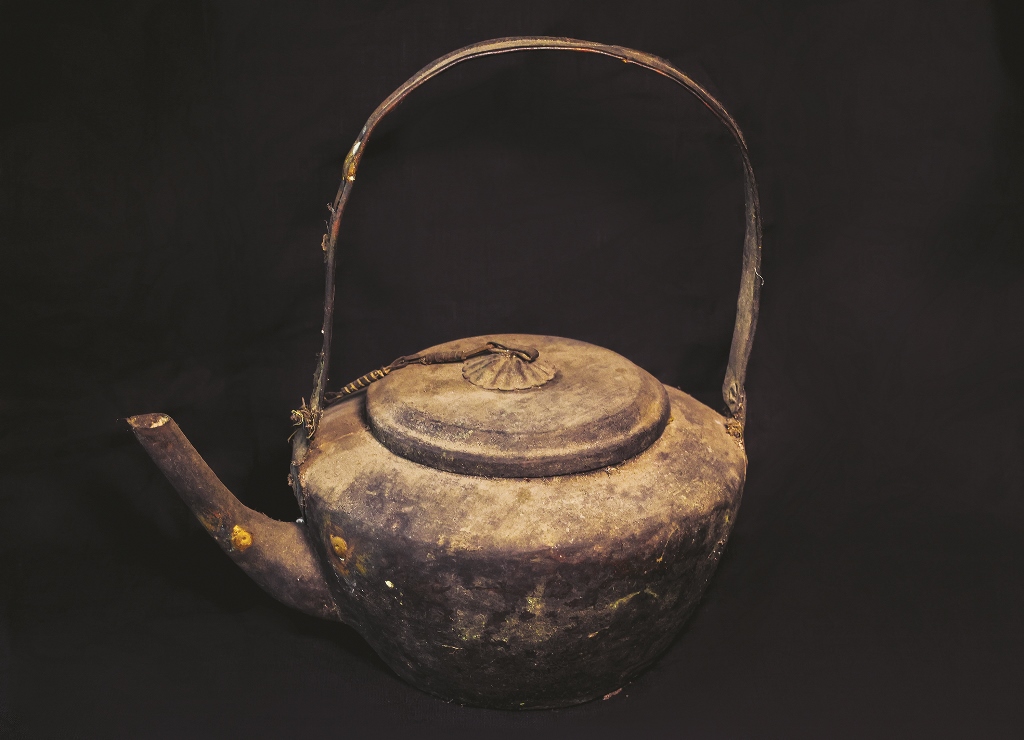 The kettle made of flattened bronze with high curved handle to avoid hot burn